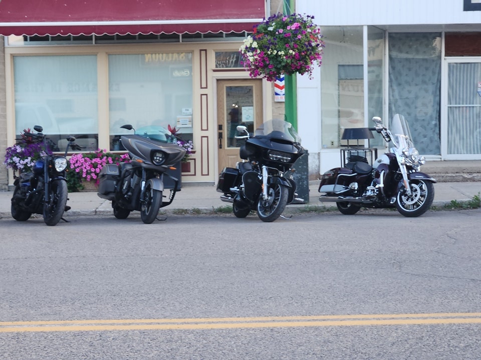 Bikes parked outside a small-town storefront with purple flower baskets