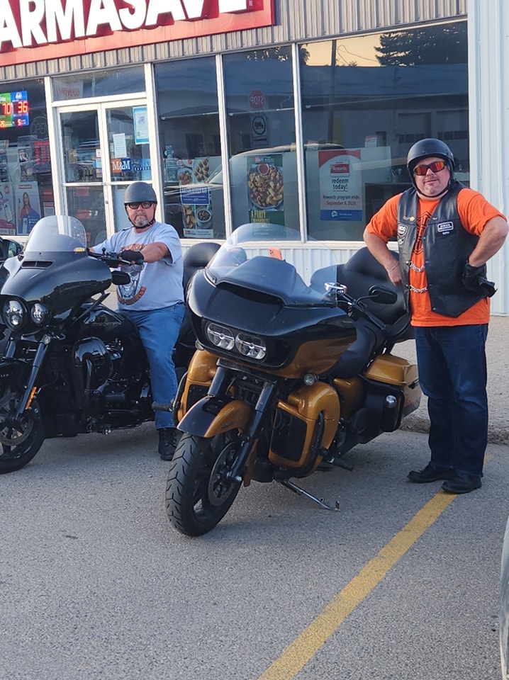 Two members posing with their bikes outside a Pharmasave on a chapter ride