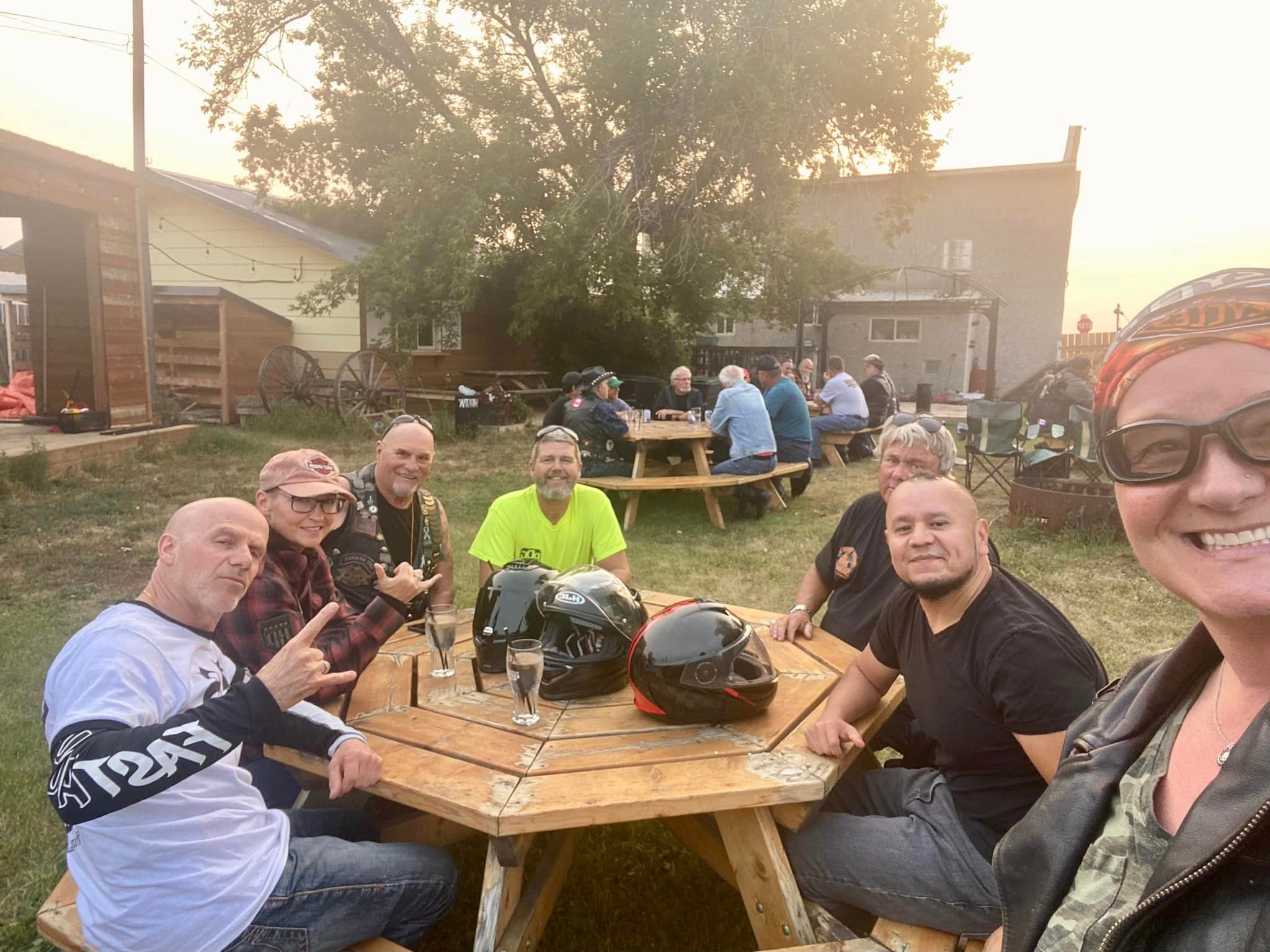 Chapter members gathered at outdoor picnic tables at sunset on a ride stop