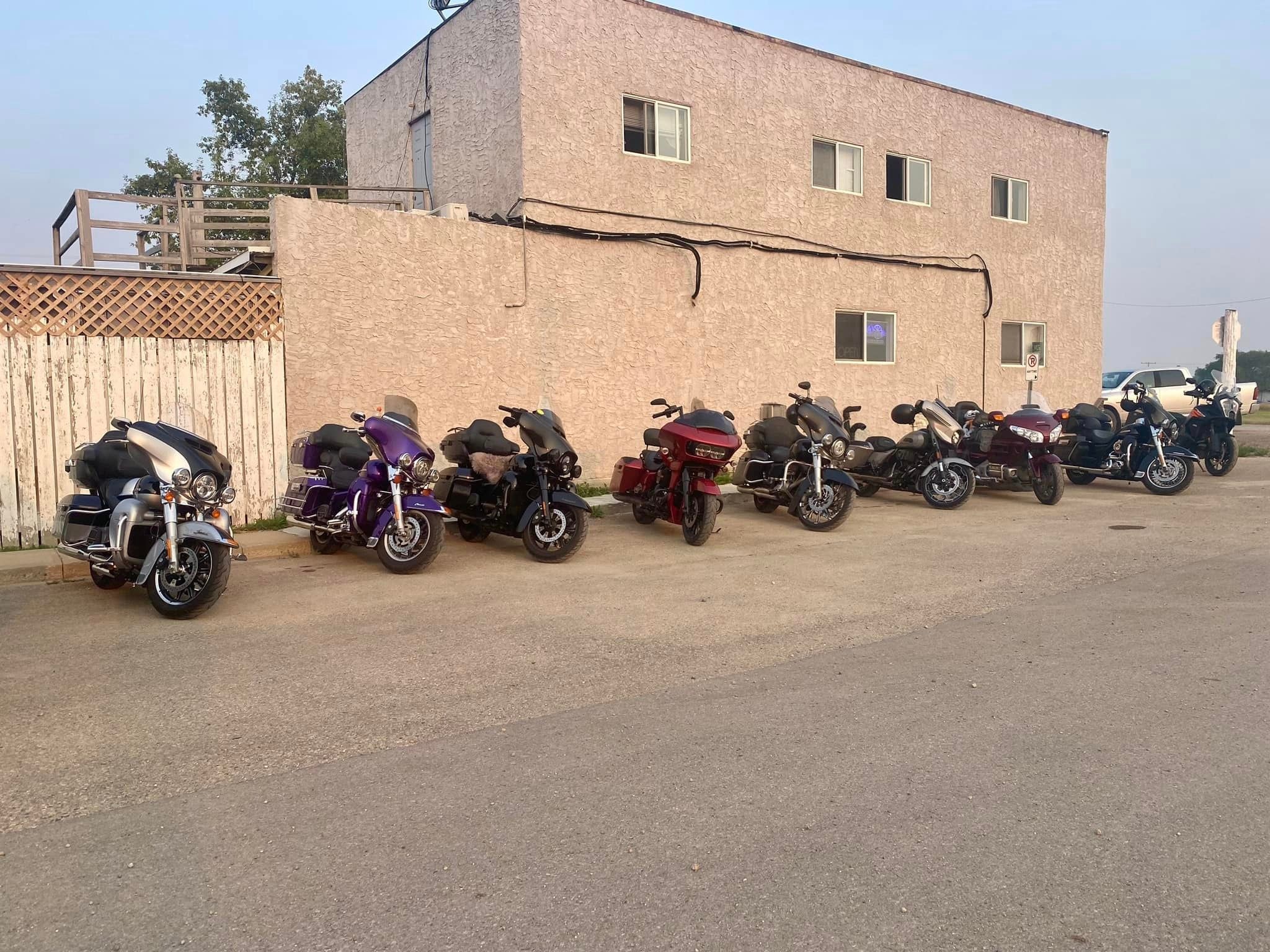 Chapter bikes parked outside a stucco building at dusk on a ride stop