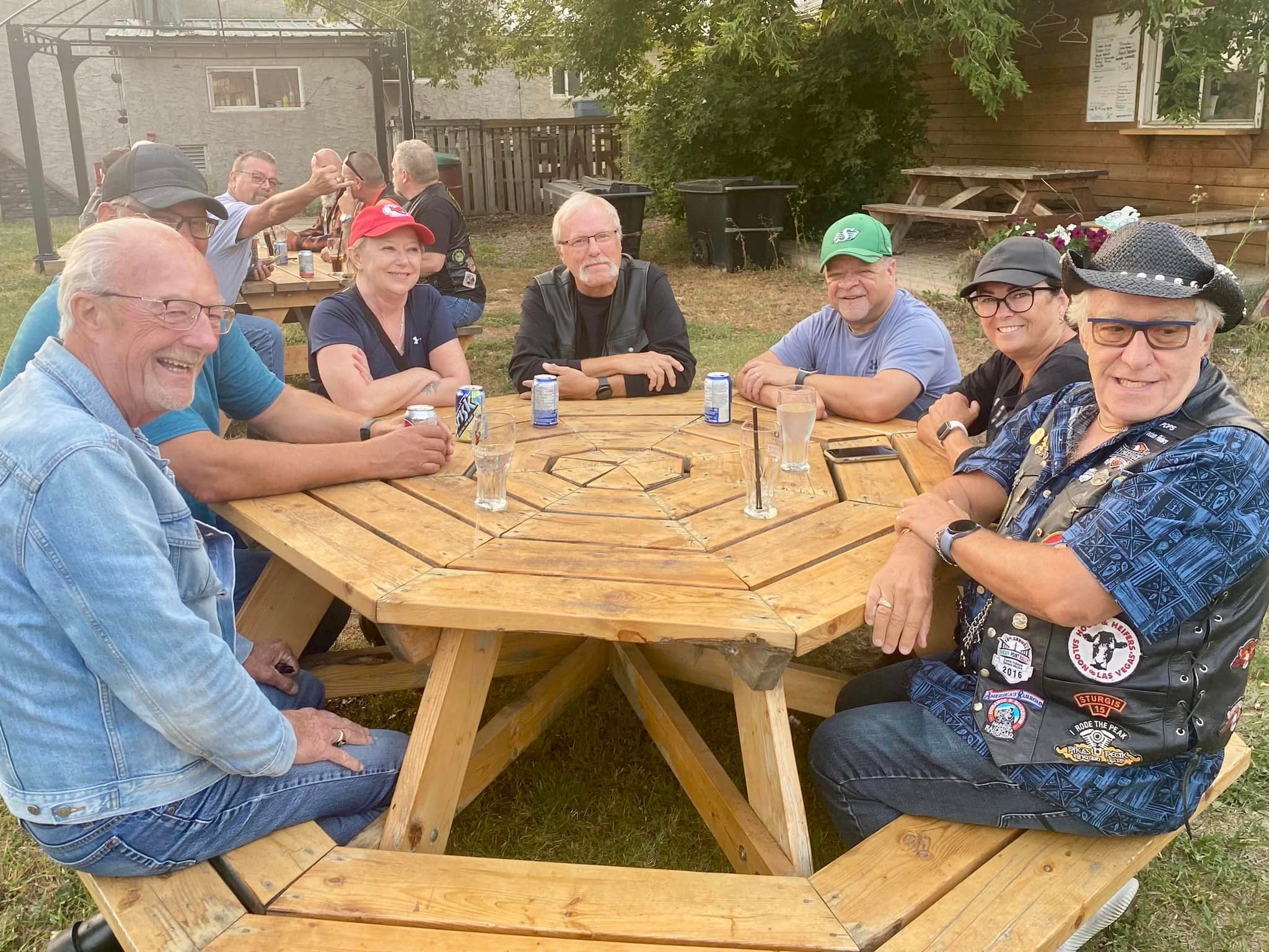 Chapter members gathered around an octagonal picnic table at an outdoor bar