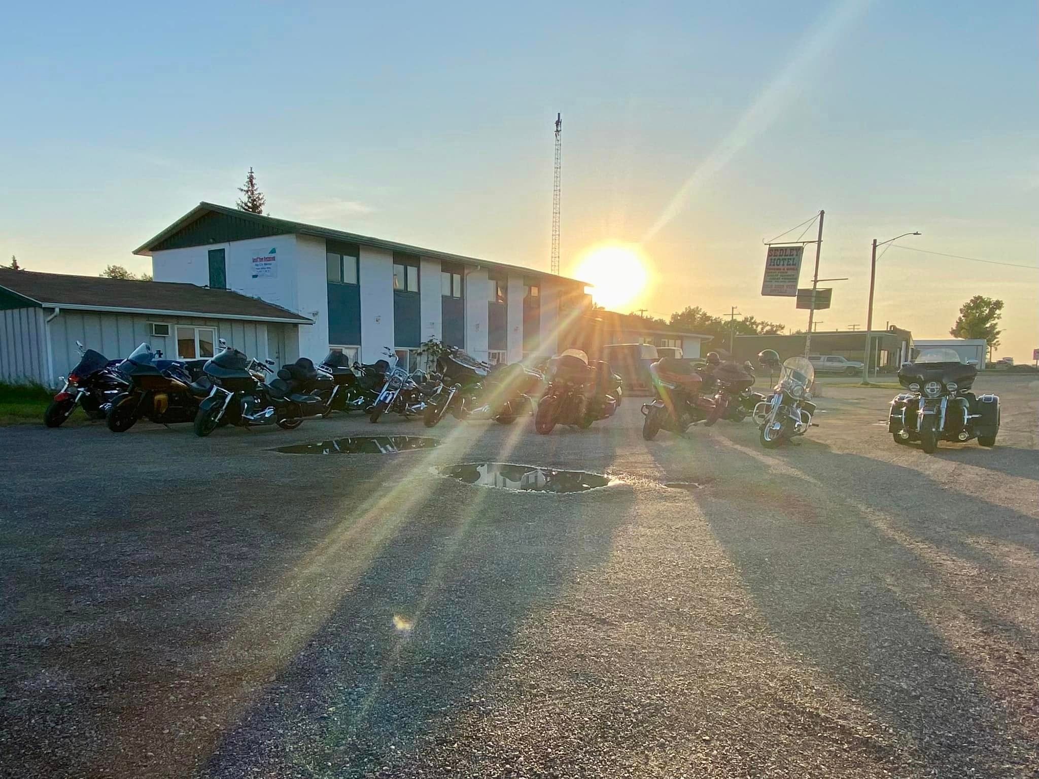 Chapter bikes lined up outside the Sedley Hotel at sunset on a ride stop