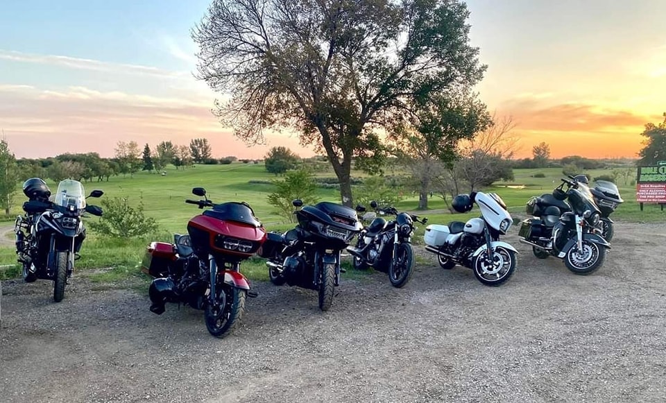 Five bikes lined up at a golf course at sunset on a chapter ride