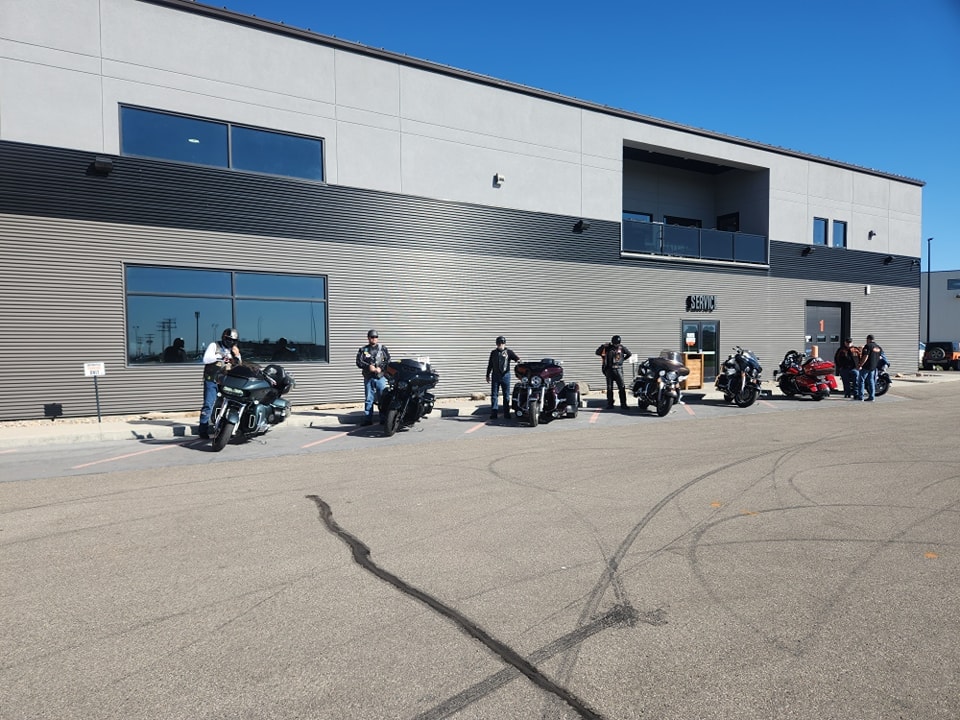Riders and bikes gathered outside the Prairie Harley-Davidson service bay on a sunny day
