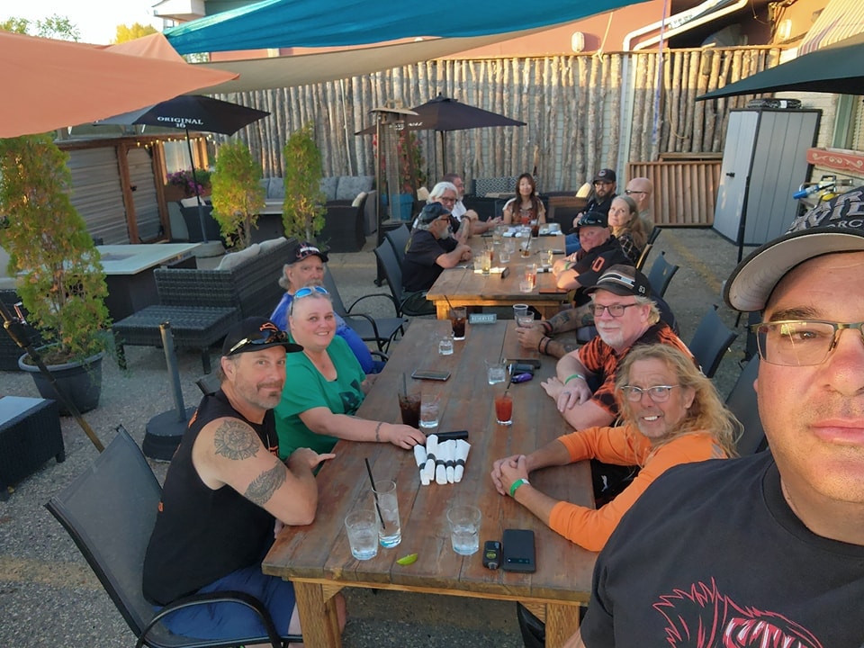 Chapter members gathered around a long wooden table on a restaurant patio at sunset