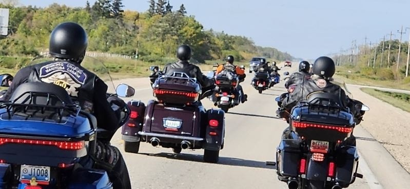 Line of chapter bikes rolling down a prairie highway with Winnipeg Chapter riders leading the pack