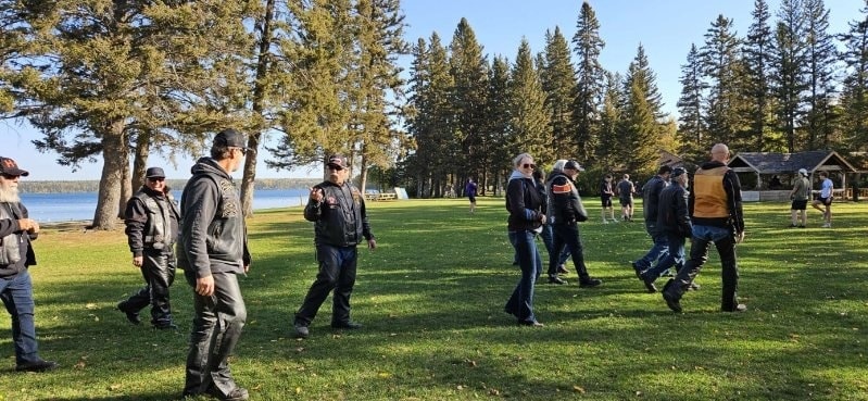 Chapter members walking across a green lakeside park at a ride destination