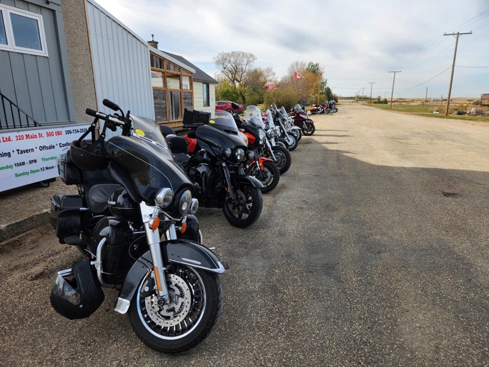 Row of chapter Harley-Davidsons parked outside a small-town tavern on a prairie ride