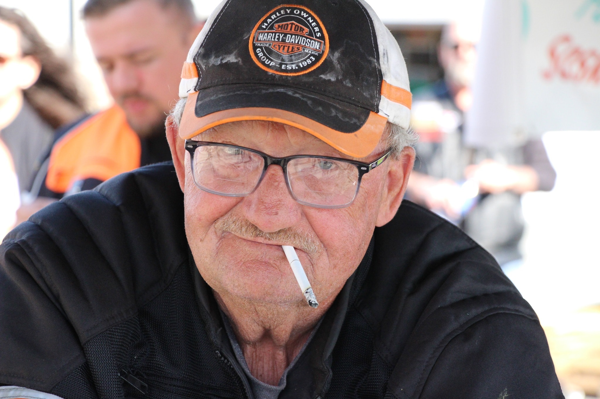 Chapter member in a HOG cap smiling at the 2024 Breast Cancer Awareness Ride breakfast