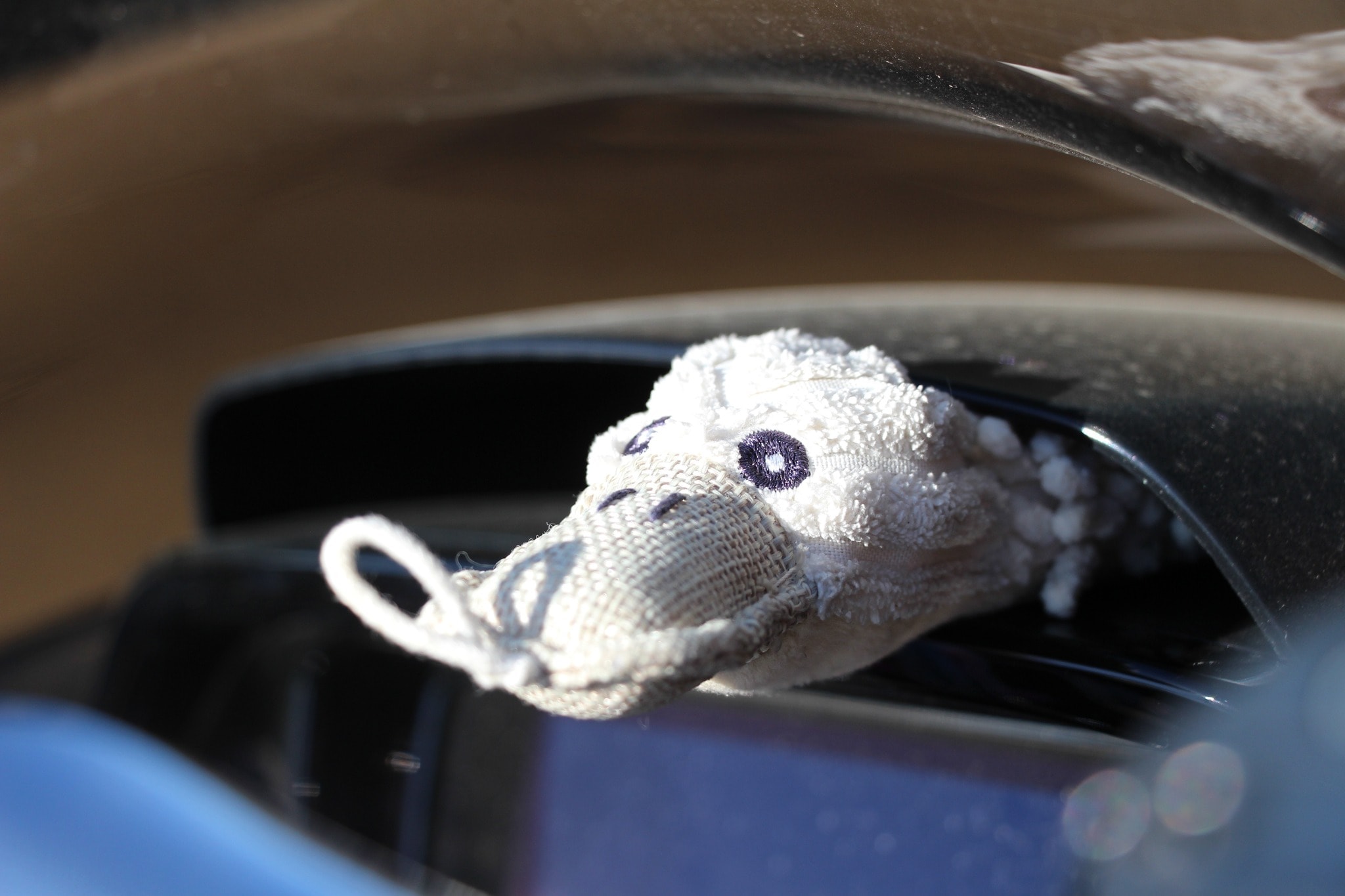 Small knitted mascot peeking out of a car window at the charity ride