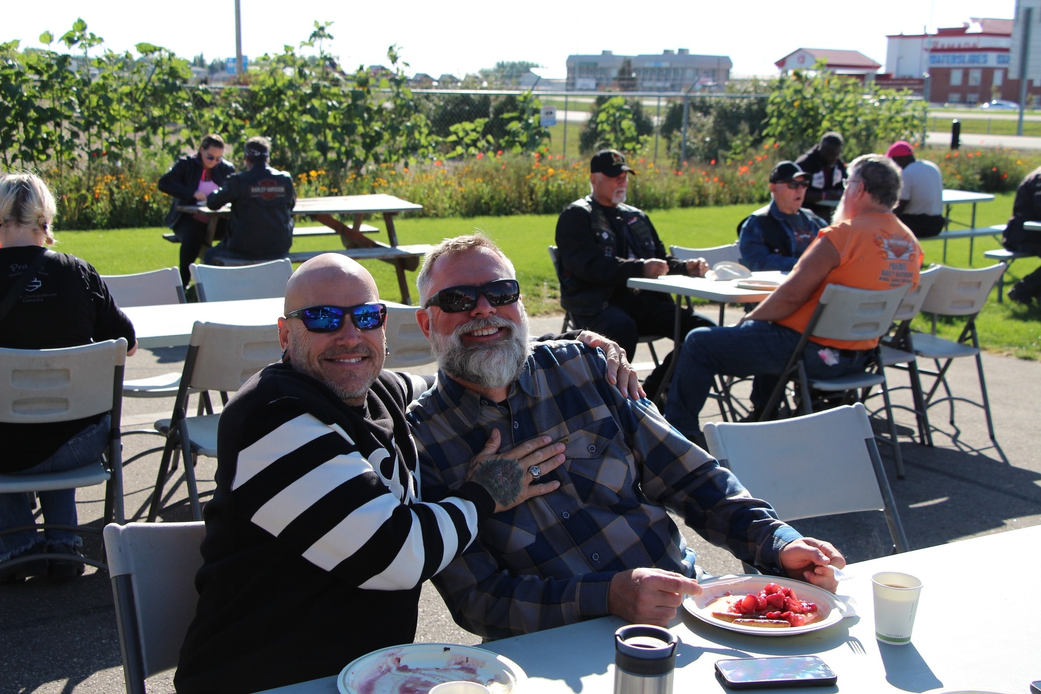 Two chapter members smiling at an outdoor table during the Breast Cancer Awareness Ride breakfast