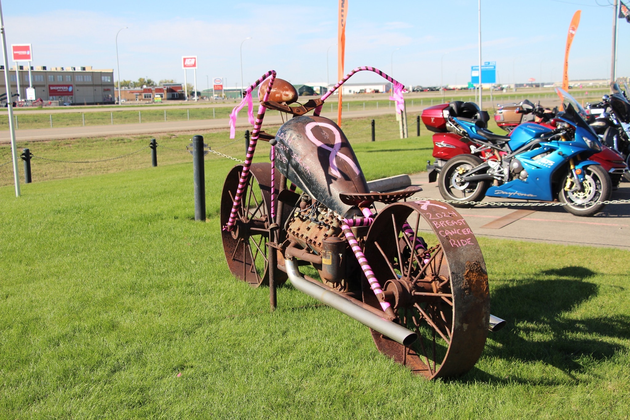 Rustic metal motorcycle sculpture decorated with pink ribbons and candy-stripe wrapping for the 2024 Breast Cancer Ride