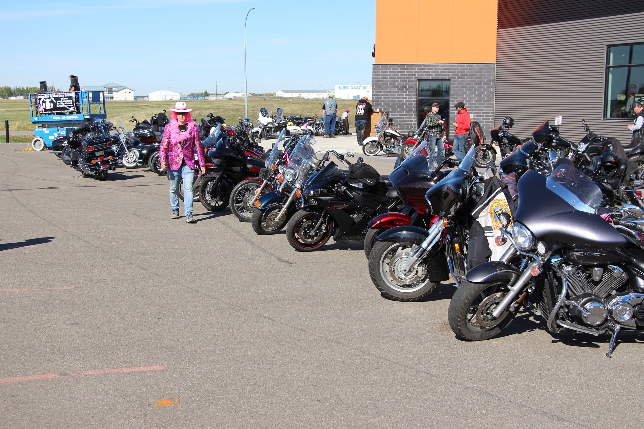 Member in a pink sequin jacket walking past rows of bikes at the Breast Cancer Awareness Ride