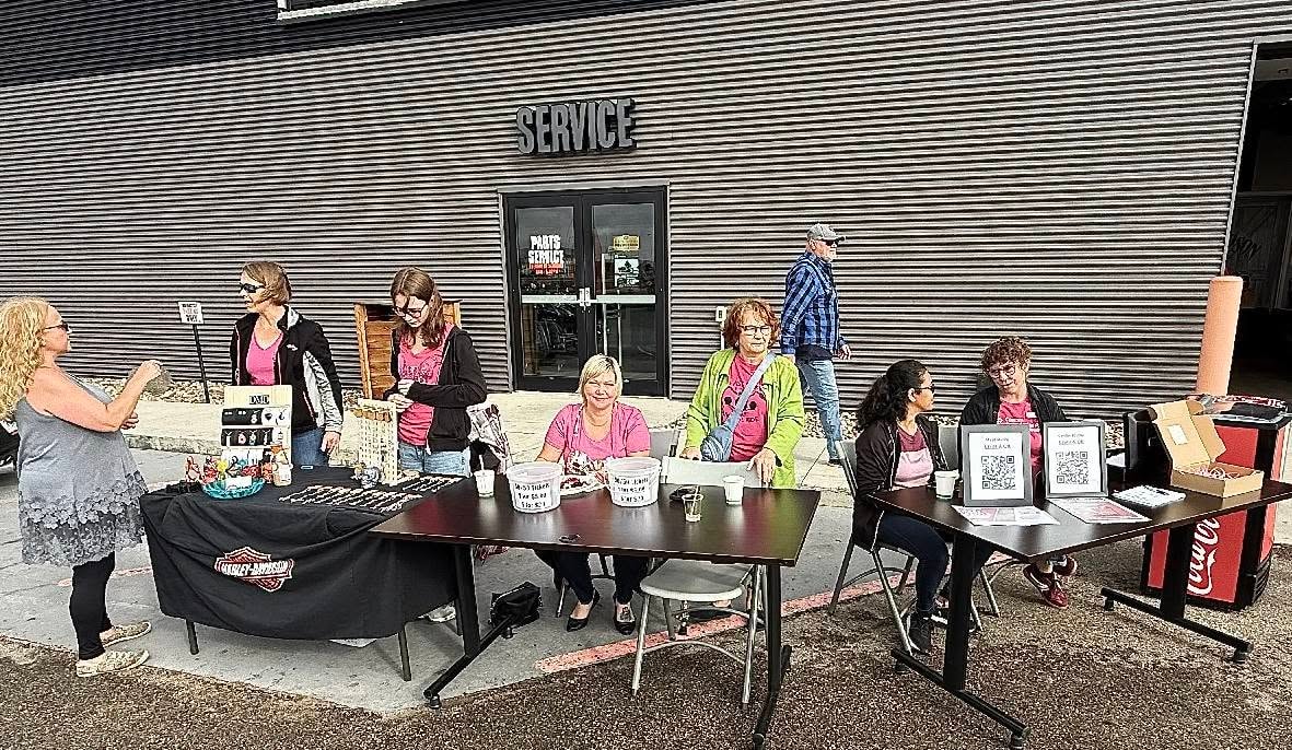 Volunteers at a Harley-Davidson-draped registration table outside the Prairie HD service bay at the 2025 Breast Cancer Awareness Ride