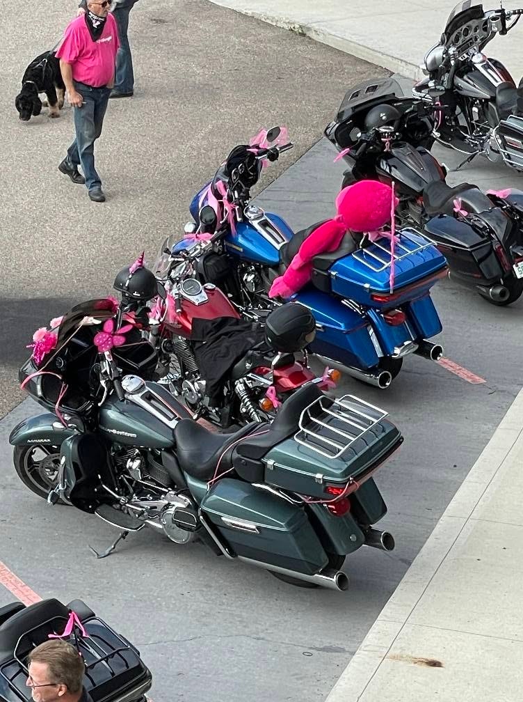 Aerial view of pink-ribbon-decorated Harley-Davidson bikes in the Prairie HD parking lot at the 2025 Breast Cancer Awareness Ride, including a fluffy pink pompom and butterfly decorations