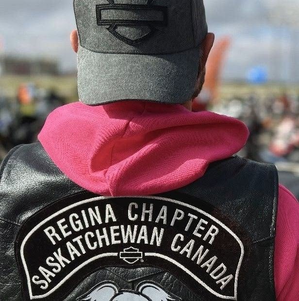 Back of a rider's leather vest showing the Regina Chapter Saskatchewan Canada patch over a pink hoodie at the 2025 Breast Cancer Awareness Ride